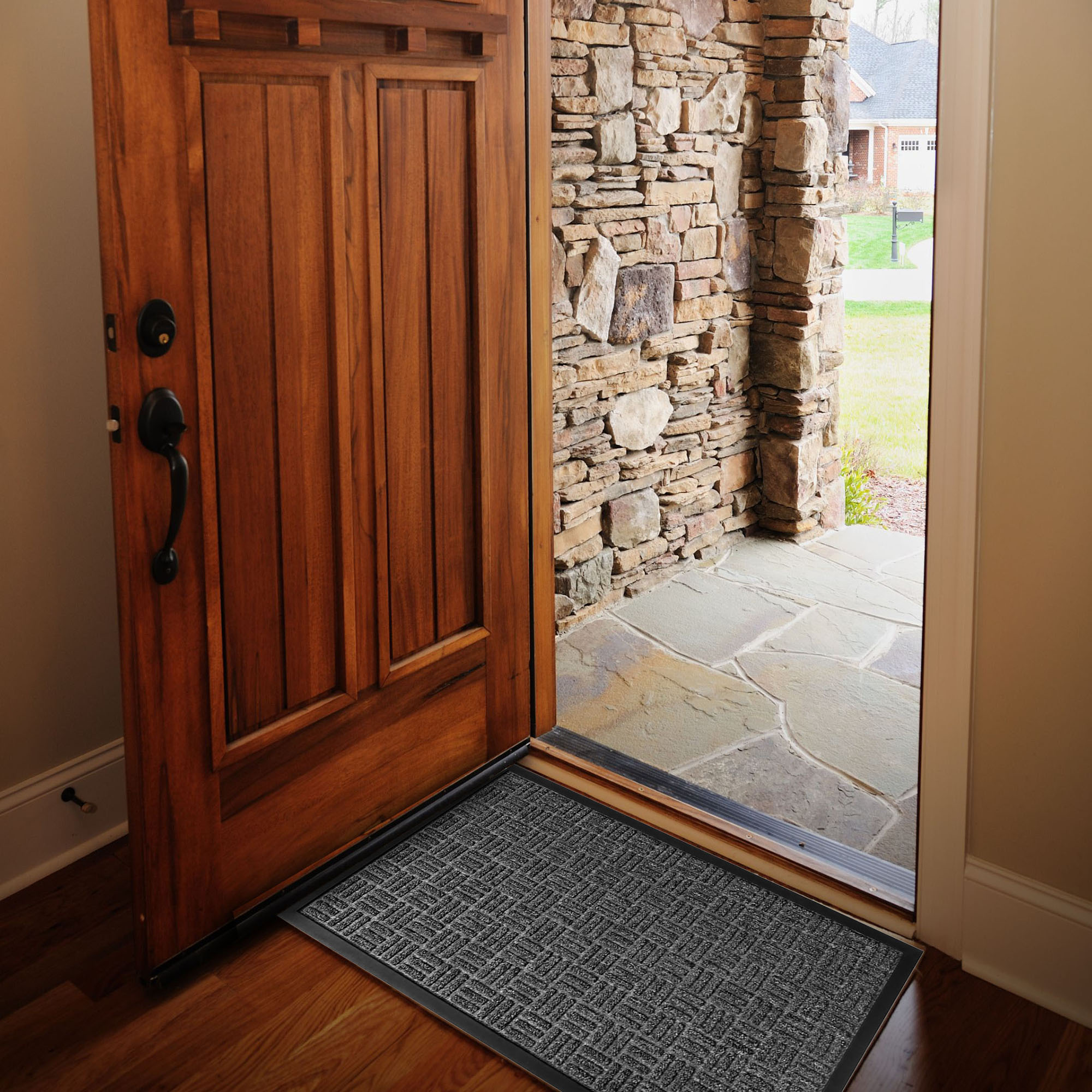 Gray checkerboard doormat inside open wooden front door on hardwood floor