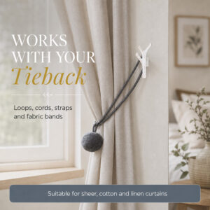 White branch tieback hook holding a curtain with a cord and pompom tieback on sheer linen drapes