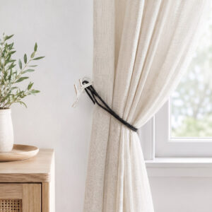 White and gold branch holdback gathering a linen curtain by a window in a neutral living room