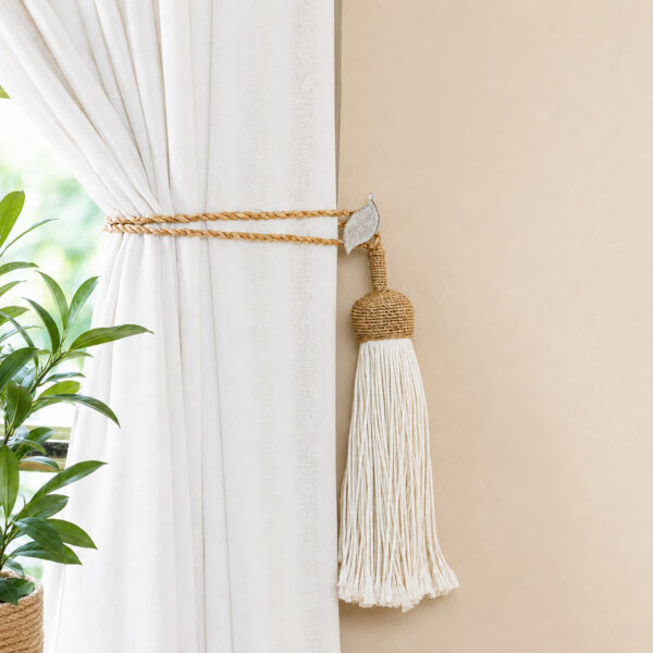 White and gold leaf holdback gathering neutral drapes with a jute rope tassel tieback in a living room