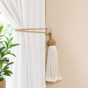 White and gold leaf holdback gathering neutral drapes with a jute rope tassel tieback in a living room