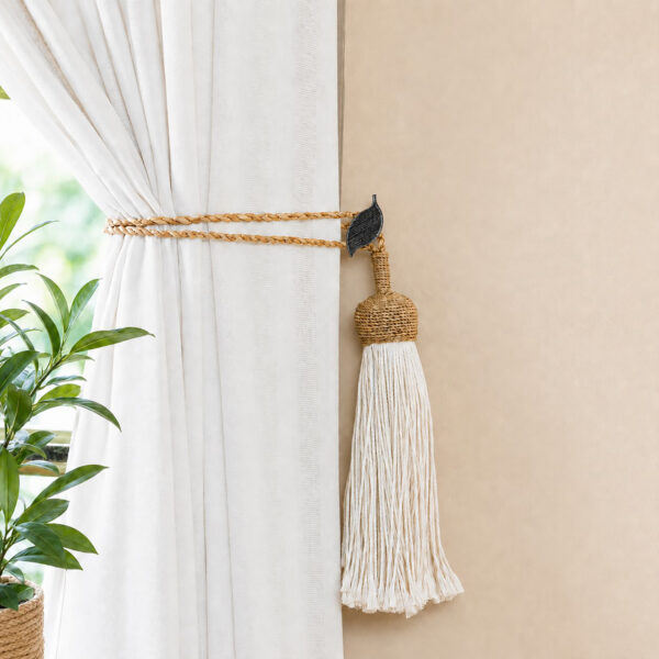 Black and silver leaf holdback gathering neutral drapes with a jute rope tassel tieback in a living room