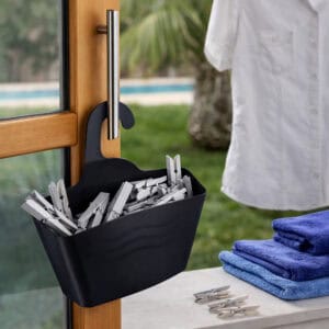 Black hanging shower caddy filled with clothespins hanging on outdoor door handle