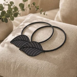 Two matching gray leaf tiebacks styled together on a linen cushion