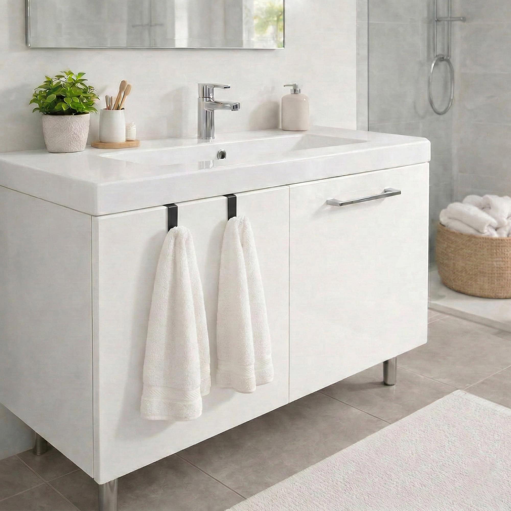"Two white towels hanging from black hooks on bathroom vanity cabinet"
