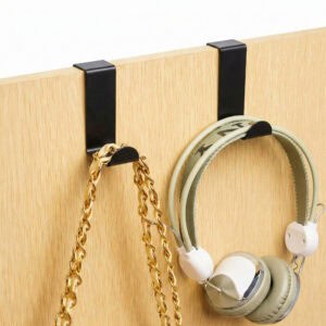 "Two black hooks on wood door holding a gold chain necklace and green headphones"