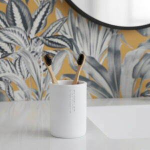 Matte white bathroom tumbler toothbrush holder with bamboo brushes on vanity