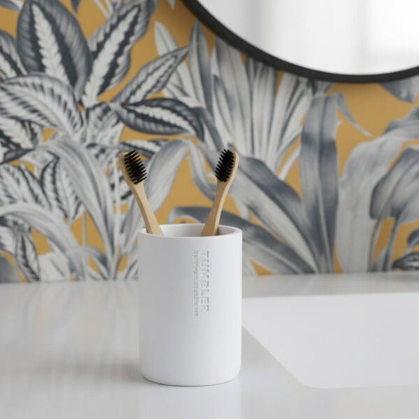 Matte white bathroom tumbler toothbrush holder with bamboo brushes on vanity