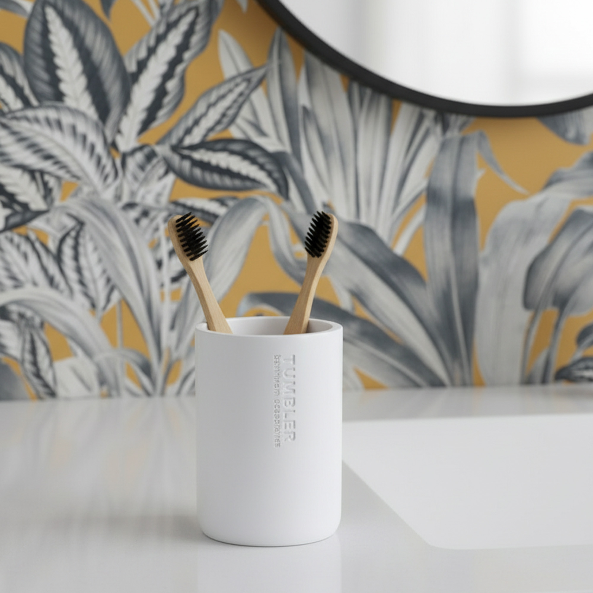 Matte white bathroom tumbler toothbrush holder with bamboo brushes on vanity