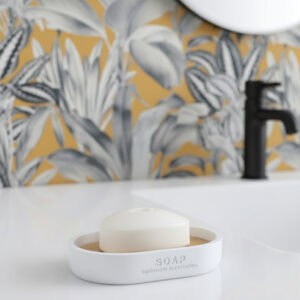 Matte white soap dish with bamboo base holding bar soap on sink