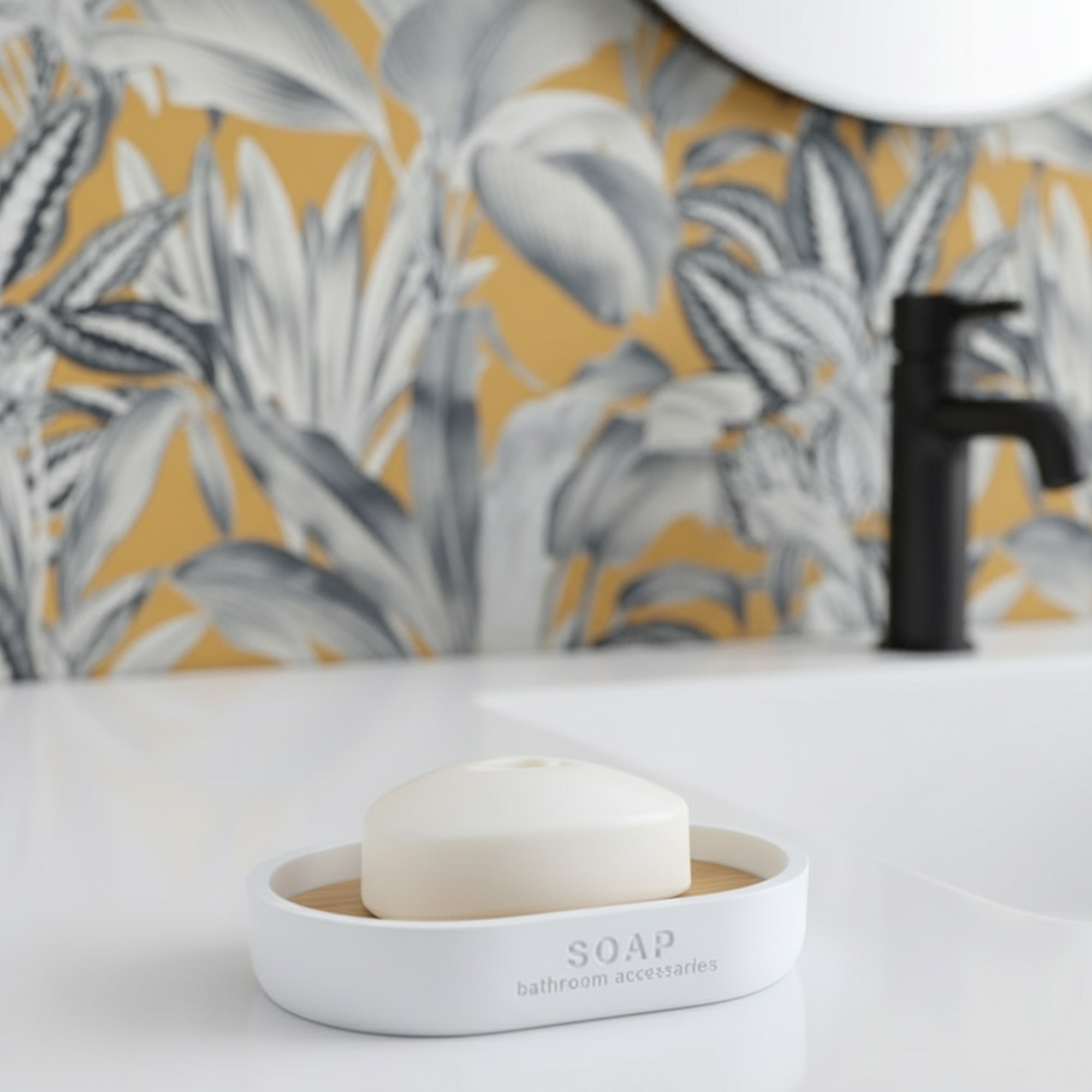 Matte white soap dish with bamboo base holding bar soap on sink