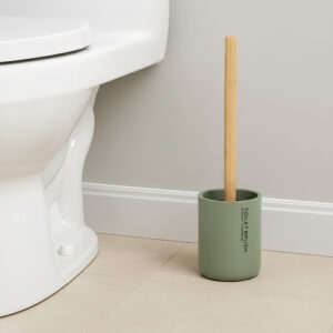 Green toilet brush with bamboo handle in matching holder placed beside toilet