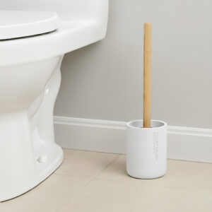 White toilet brush with bamboo handle in matching holder placed beside toilet