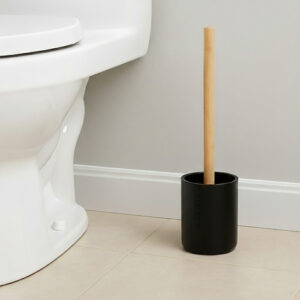 Black toilet brush with bamboo handle in matching holder placed beside toilet