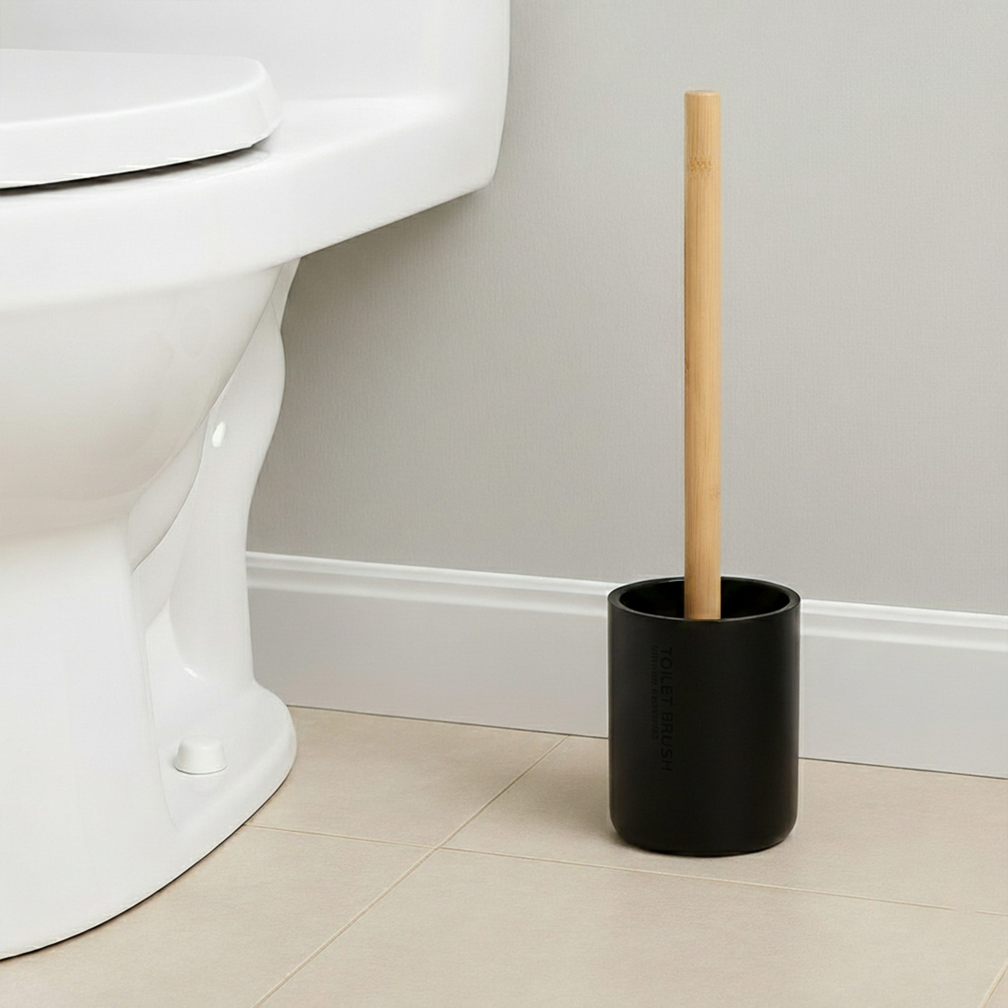 Black toilet brush with bamboo handle in matching holder placed beside toilet