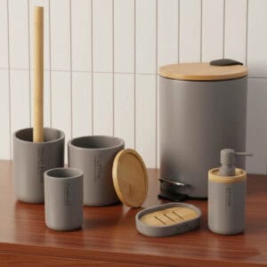 Gray bathroom accessory set with bamboo accents on wooden vanity