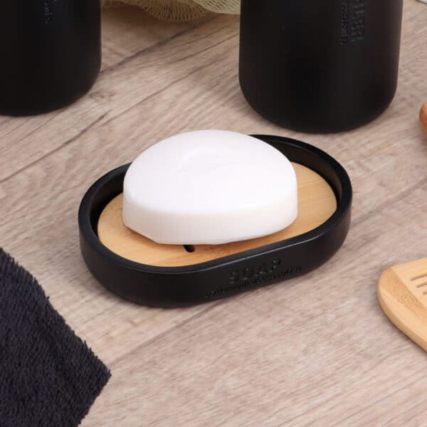Black oval soap dish with slotted bamboo insert close-up