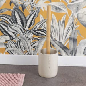Beige toilet brush and holder displayed on bathroom floor with botanical wallpaper backdrop