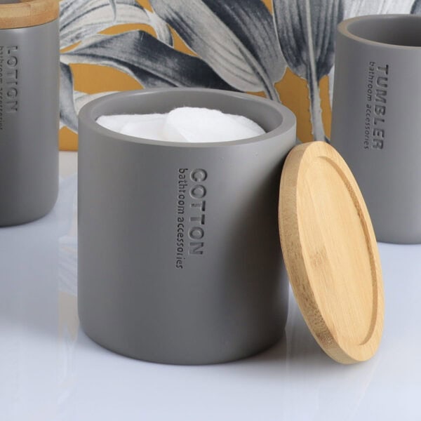 Gray cotton jar with bamboo lid removed showing cotton balls inside, part of matching bathroom set