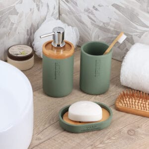 Lotion dispenser, tumbler, and soap dish in green with bamboo details showcased in an elegant bathroom setup.