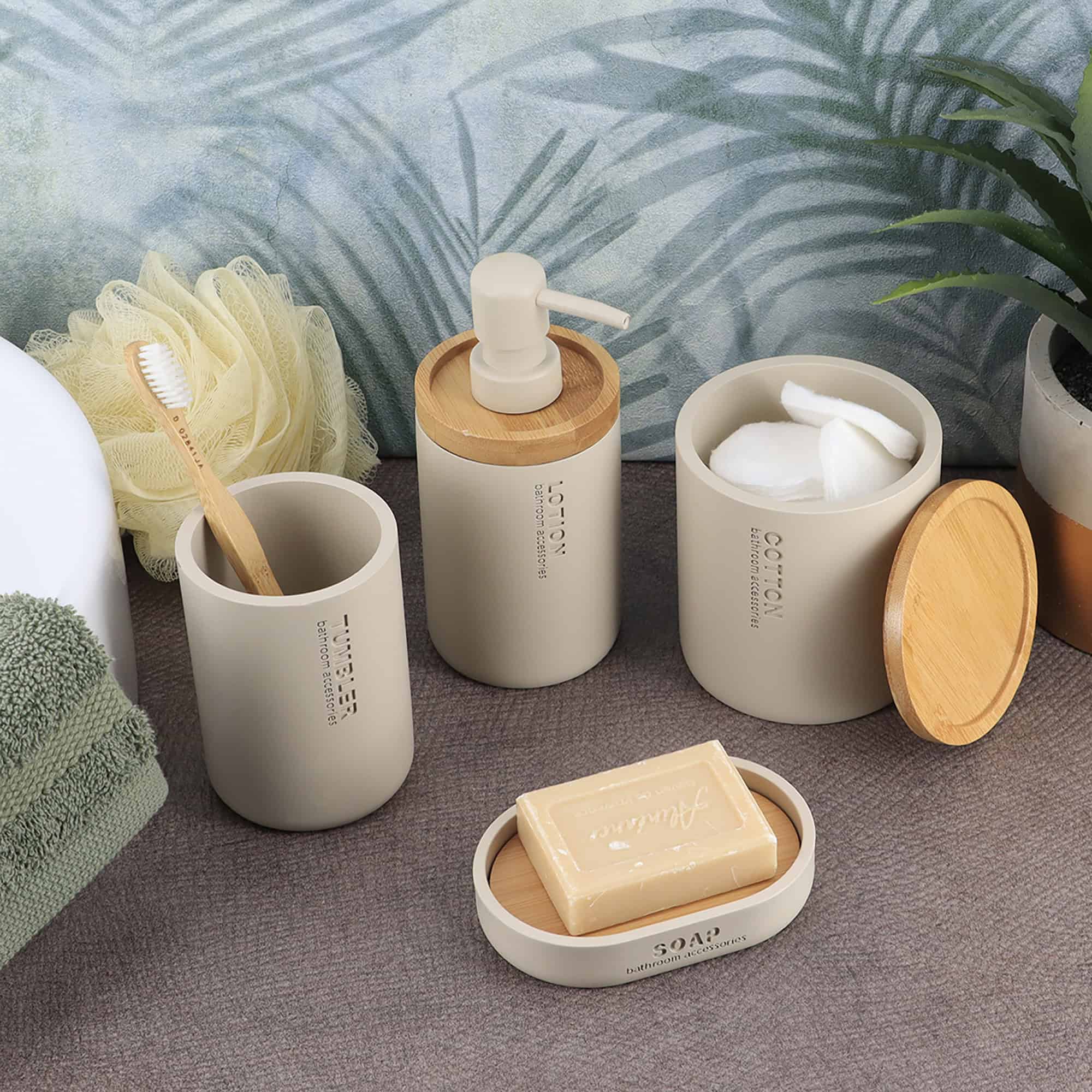 Beige bathroom accessories styled together with bamboo accents, including a lotion dispenser, tumbler, soap dish, and cotton jar.