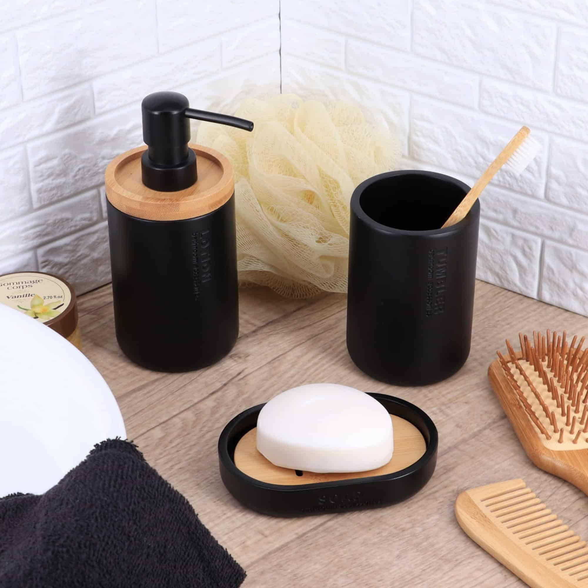 Lotion dispenser, tumbler, and soap dish in black with bamboo details showcased in an elegant bathroom setup.