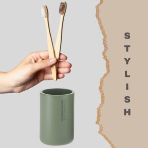 Green toothbrush holder with bamboo brushes in modern bathroom