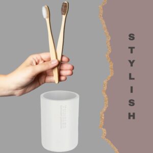White toothbrush holder with bamboo brushes in modern bathroom