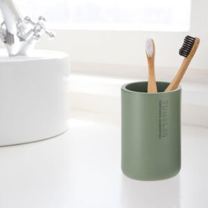 Modern green bathroom tumbler used as toothbrush holder on vanity
