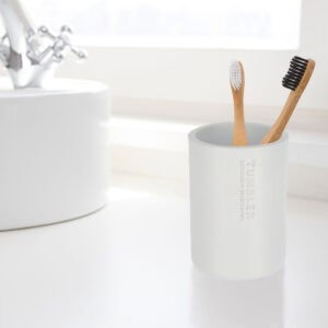 Modern white bathroom tumbler used as toothbrush holder on vanity