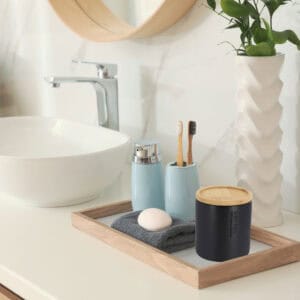 Matte black cotton jar with bamboo lid on bathroom vanity tray with blue accessories and geometric planter