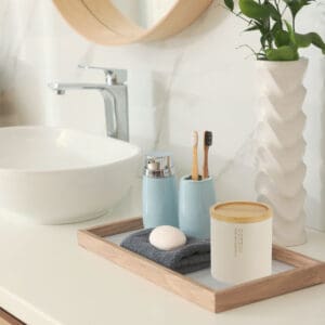 Beige cotton jar with bamboo lid styled on a bathroom tray, surrounded by matching accessories and a minimalist sink setup.