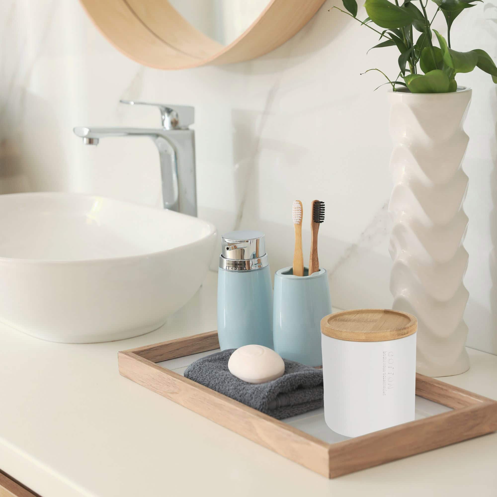 Modern bathroom vanity tray with white cotton jar, blue accessories, and geometric planter