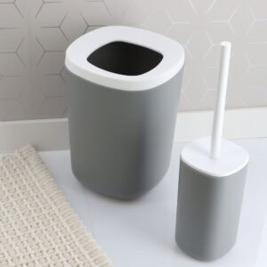 Gray trash can and toilet brush set on bathroom floor