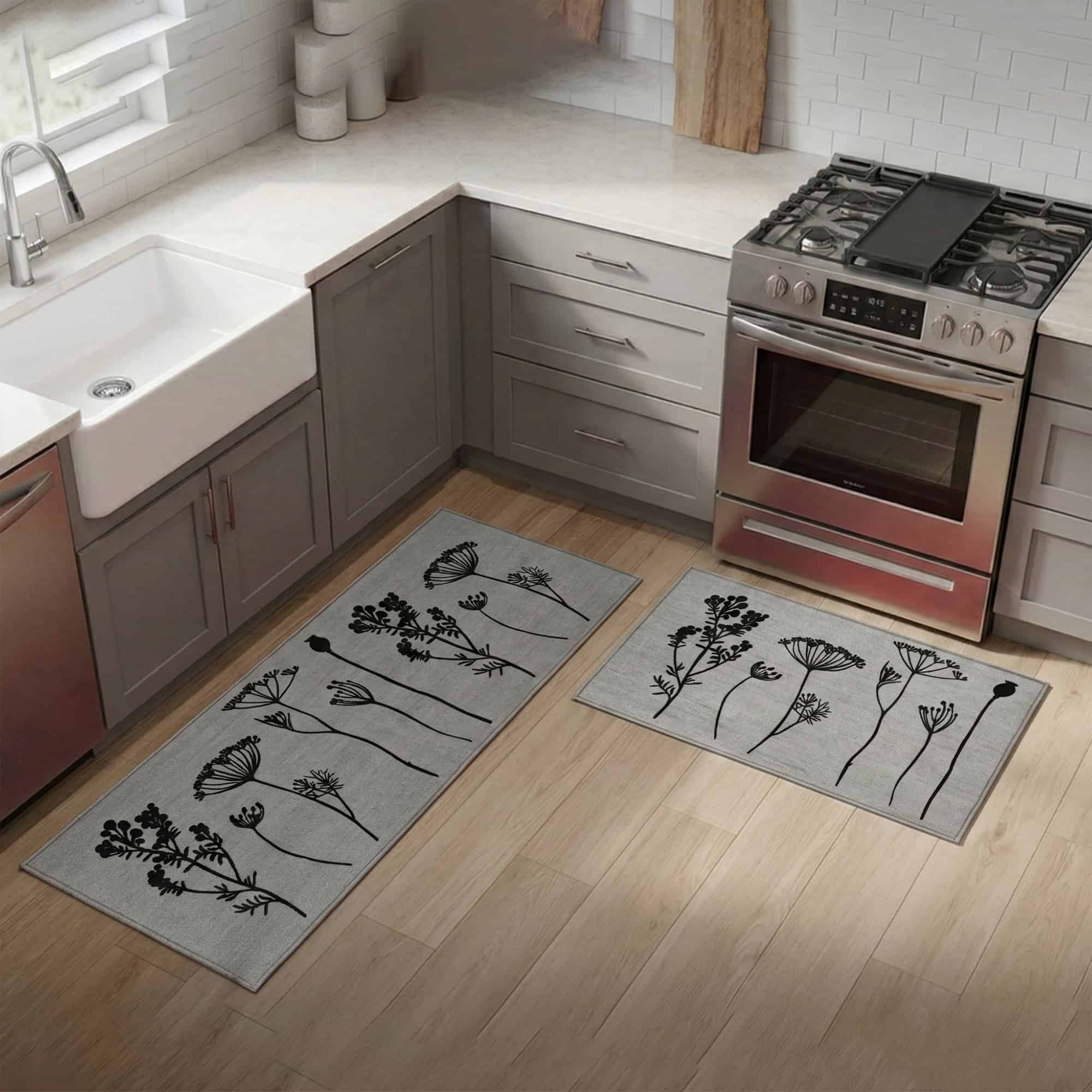 Gray floral mat and runner set placed on hardwood beside a farmhouse sink and stove, black botanical stems bringing pattern to a bright modern kitchen.