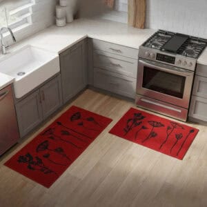 Red floral mat and runner set placed on hardwood beside a farmhouse sink and stove, black botanical stems adding a bold accent to the kitchen.