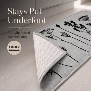 Gray floral kitchen runner with one corner folded back to reveal the anti slip dotted latex backing that grips hard floors.