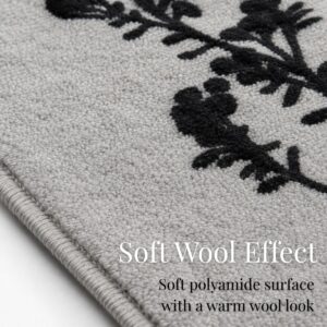 Close up of the gray rug surface showing the soft polyamide pile and crisp black botanical print with a warm wool look underfoot.