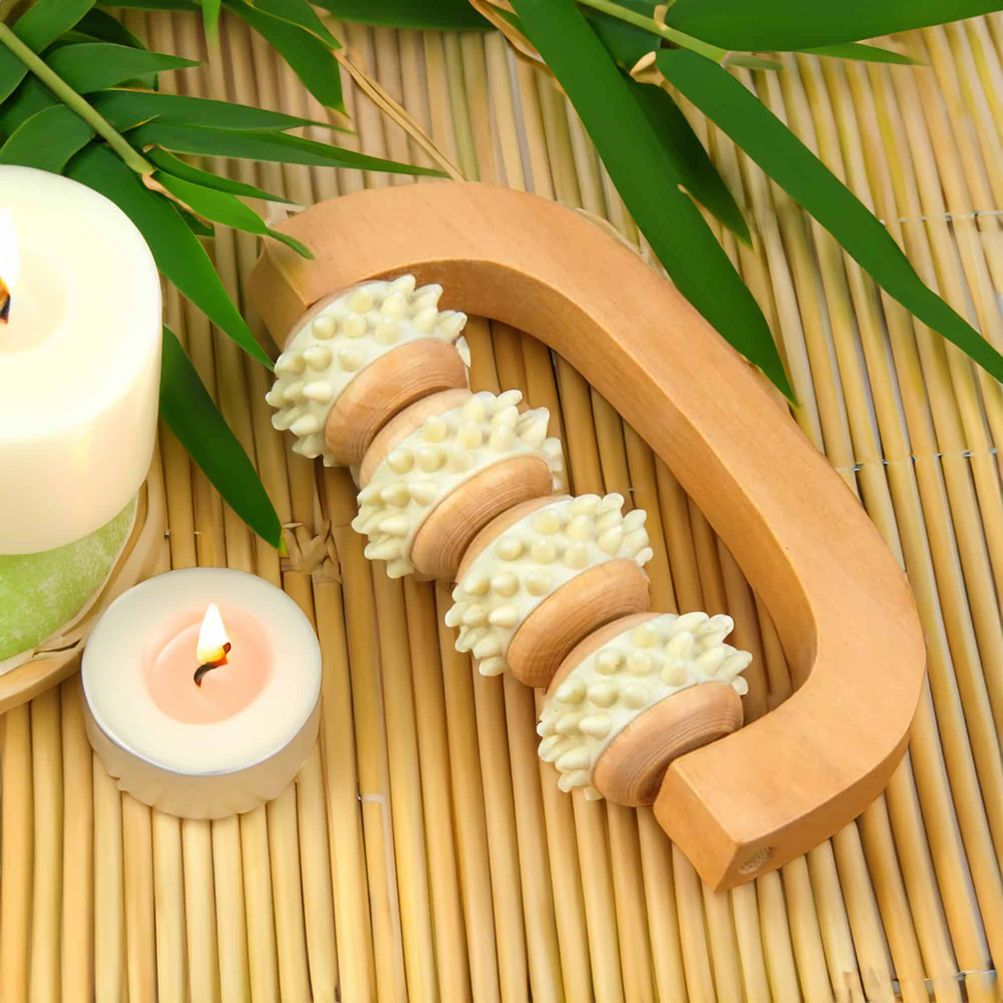 Spa-quality natural wooden massage roller with four contouring wheels, displayed on bamboo mat with candles and greenery for a serene self-care atmosphere.