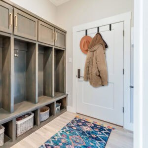 "Matte black over-door hooks holding tan jacket and orange hat on white door in mudroom entryway"