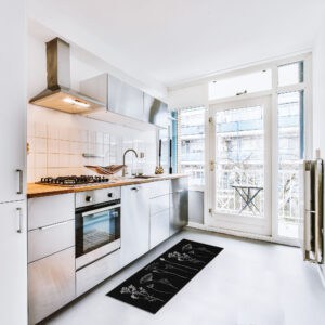 a modern kitchen in elegant white and silver with a black kitchen rug with botanical motifs