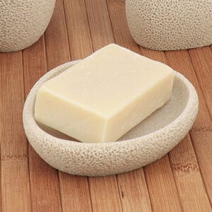 Beige sponge texture soap dish with bar soap on wooden surface