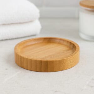 Round bamboo soap dish empty on tiled bathroom surface
