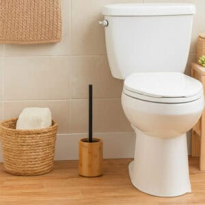 Natural bamboo toilet brush holder with black handle in modern bathroom with woven basket