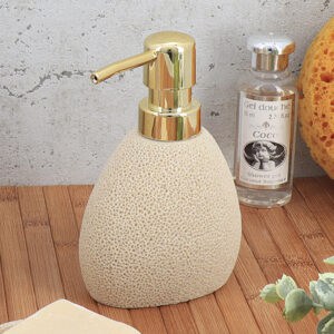 Sponge effect soap dispenser with gold pump displayed on bamboo surface with bath accessories