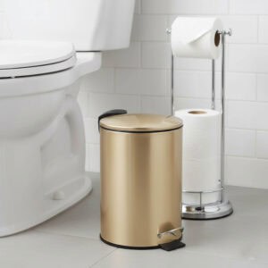 Gold pedal trash can next to toilet in modern bathroom