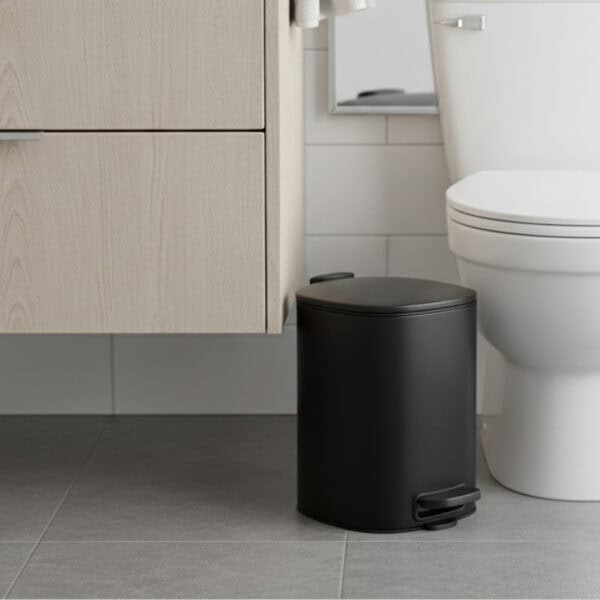 Black pedal trash can on tiled floor close-up