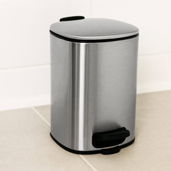 Chrome pedal trash can on tiled floor close-up