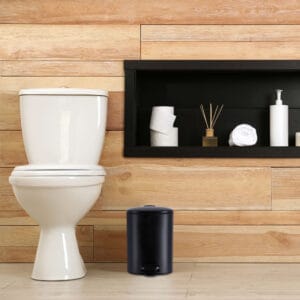 a black trash can next to toilet seat in bathroom environment