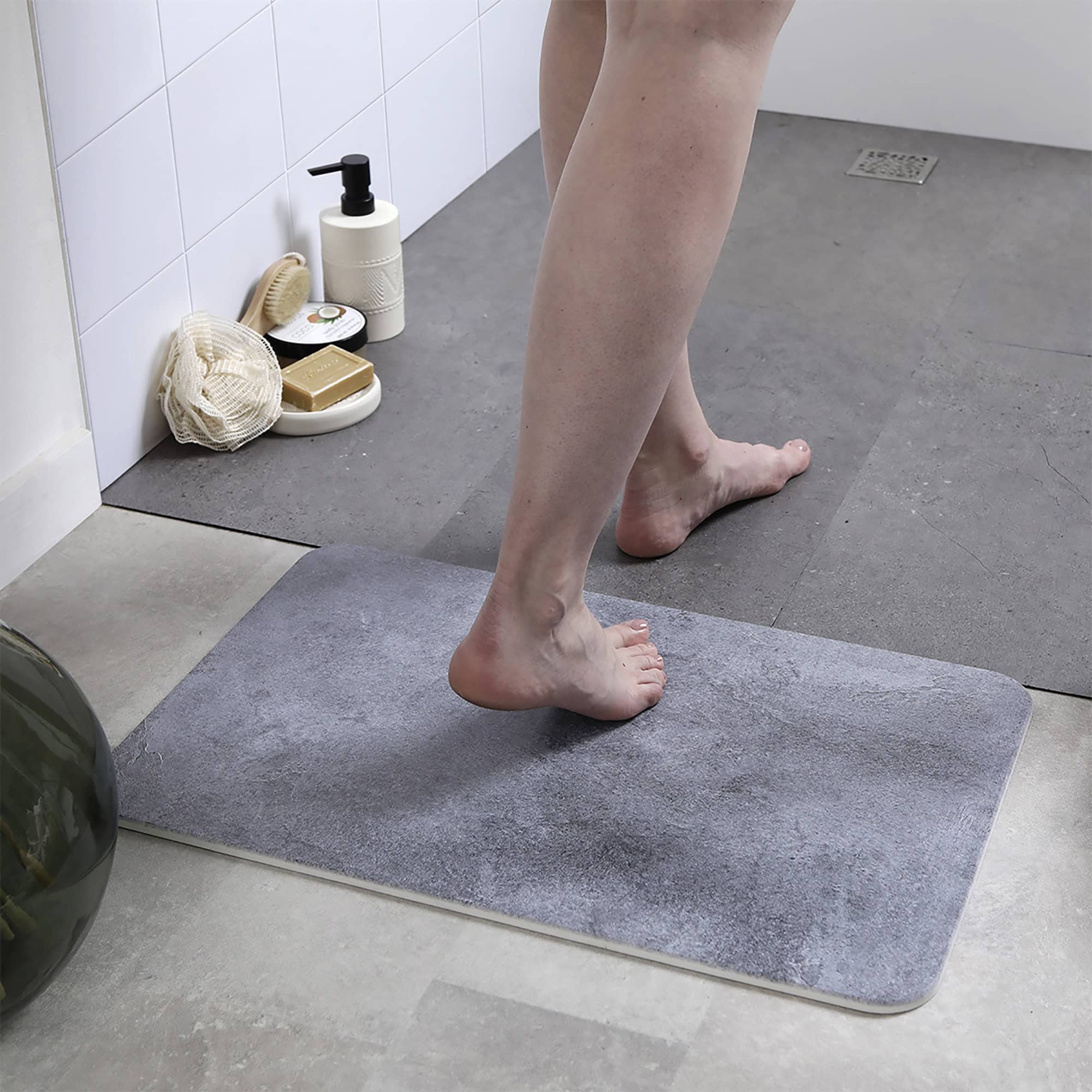 Person standing on a concrete-patterned diatomite bath mat in a modern bathroom
